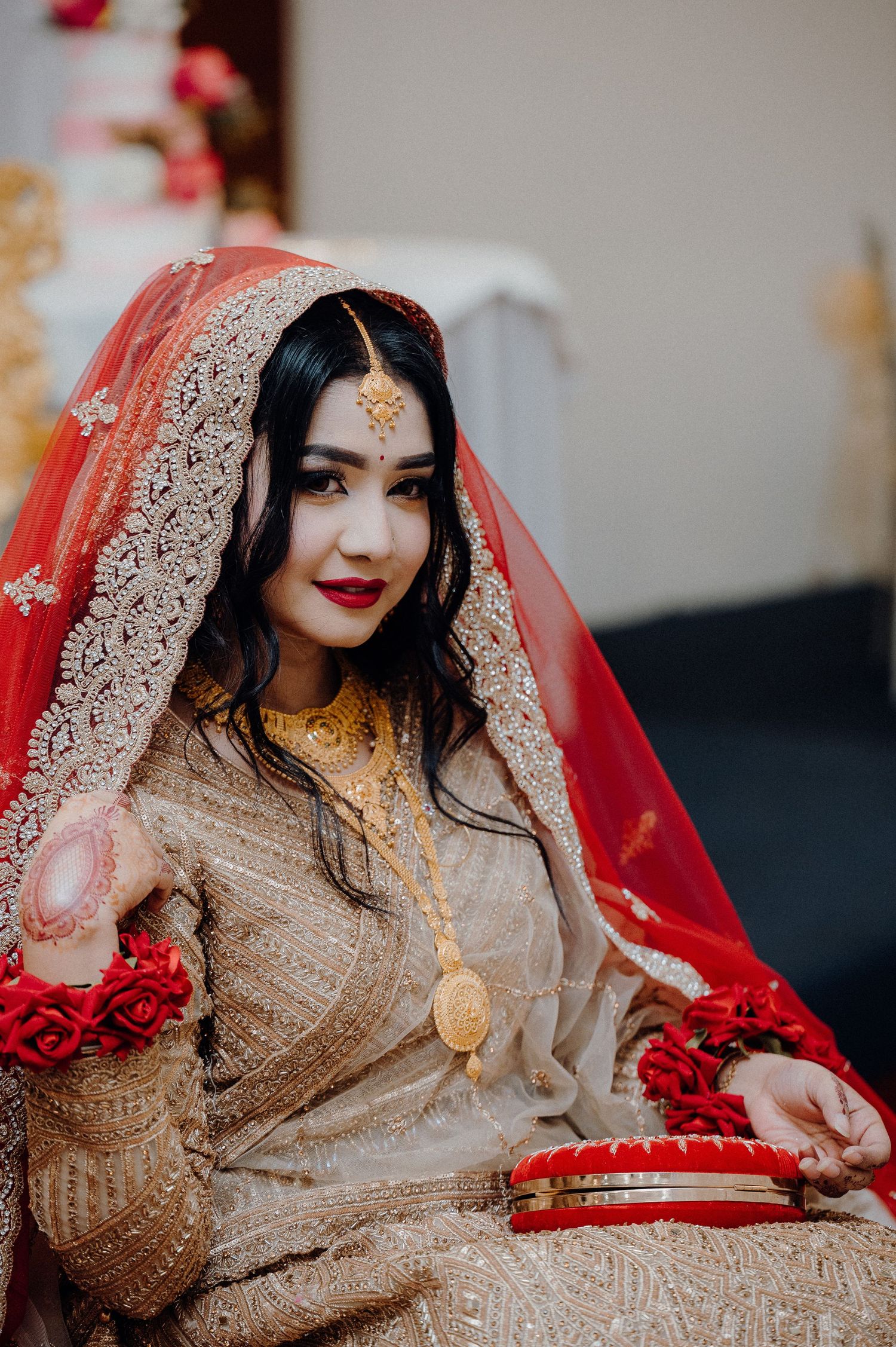 Traditional South Asian bridal attire featuring red dupatta, golden dress and floral accessories.