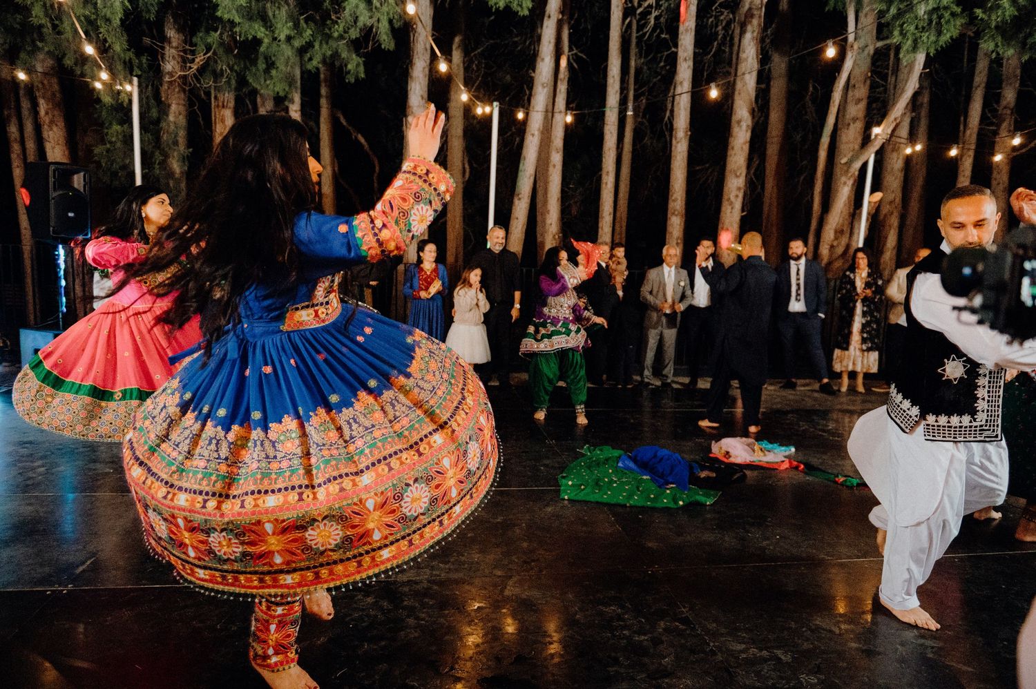 Performers in vibrant traditional dresses dancing at an outdoor celebration.