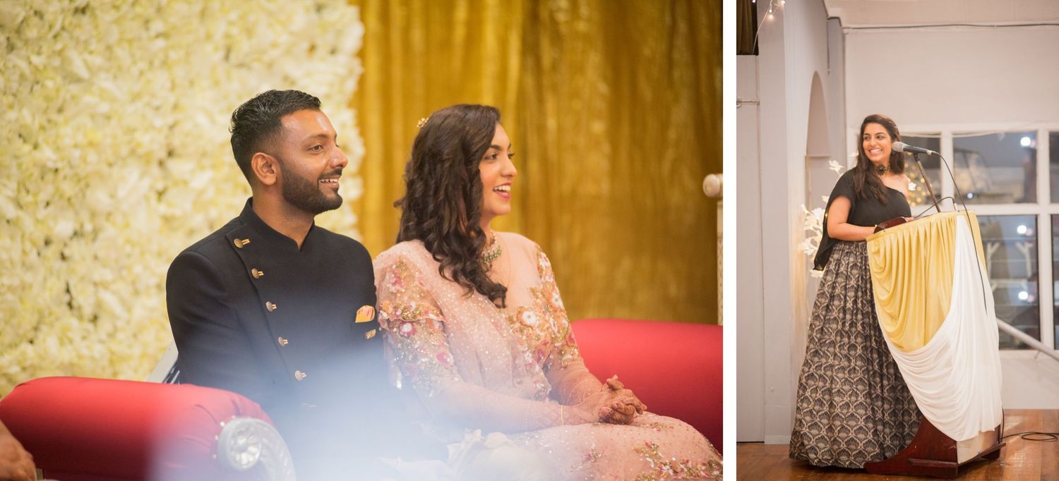 Couple seated on red sofa at formal event with gold backdrop.
