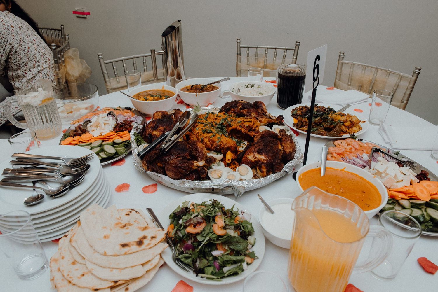 Traditional Pakistani wedding feast with various dishes including biryani, curry, and flatbreads displayed on a white tablecloth.