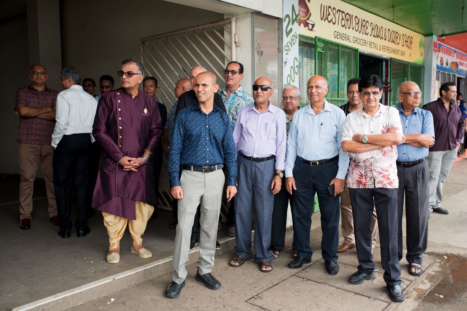 A group of guests line up outside a building during a wedding celebration.