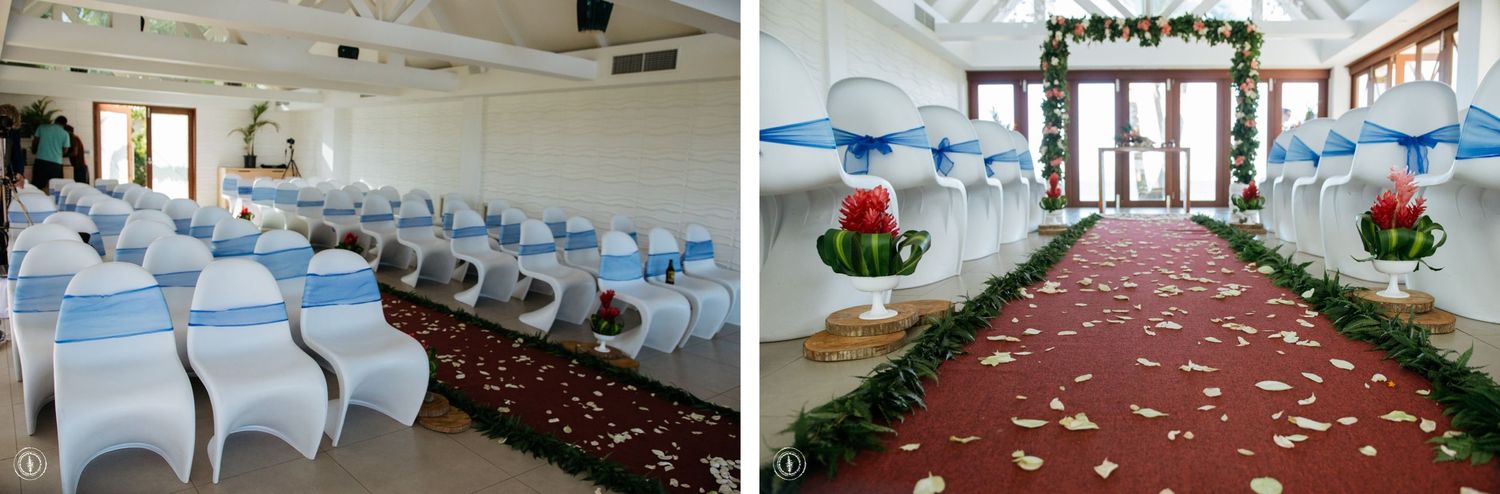 Wedding ceremony setup with white chairs and floral arch in an indoor venue.