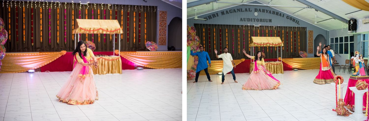 People dancing and celebrating during a traditional Indian wedding reception in a decorated auditorium.