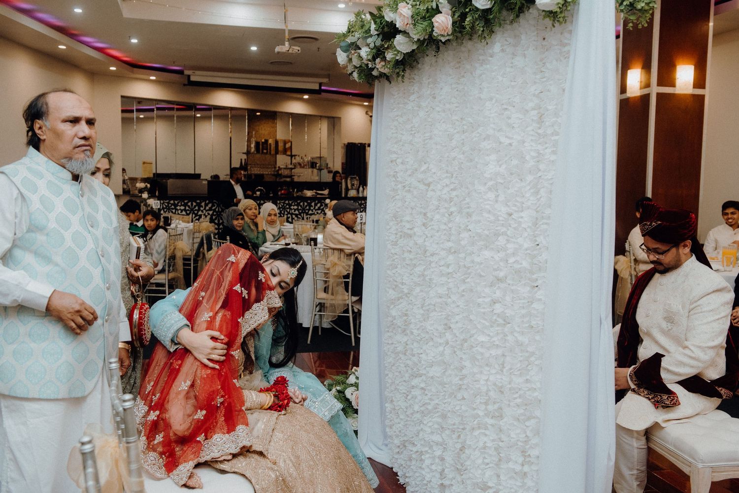 Wedding venue decorated with white drapery and floral arrangements on pillars.
