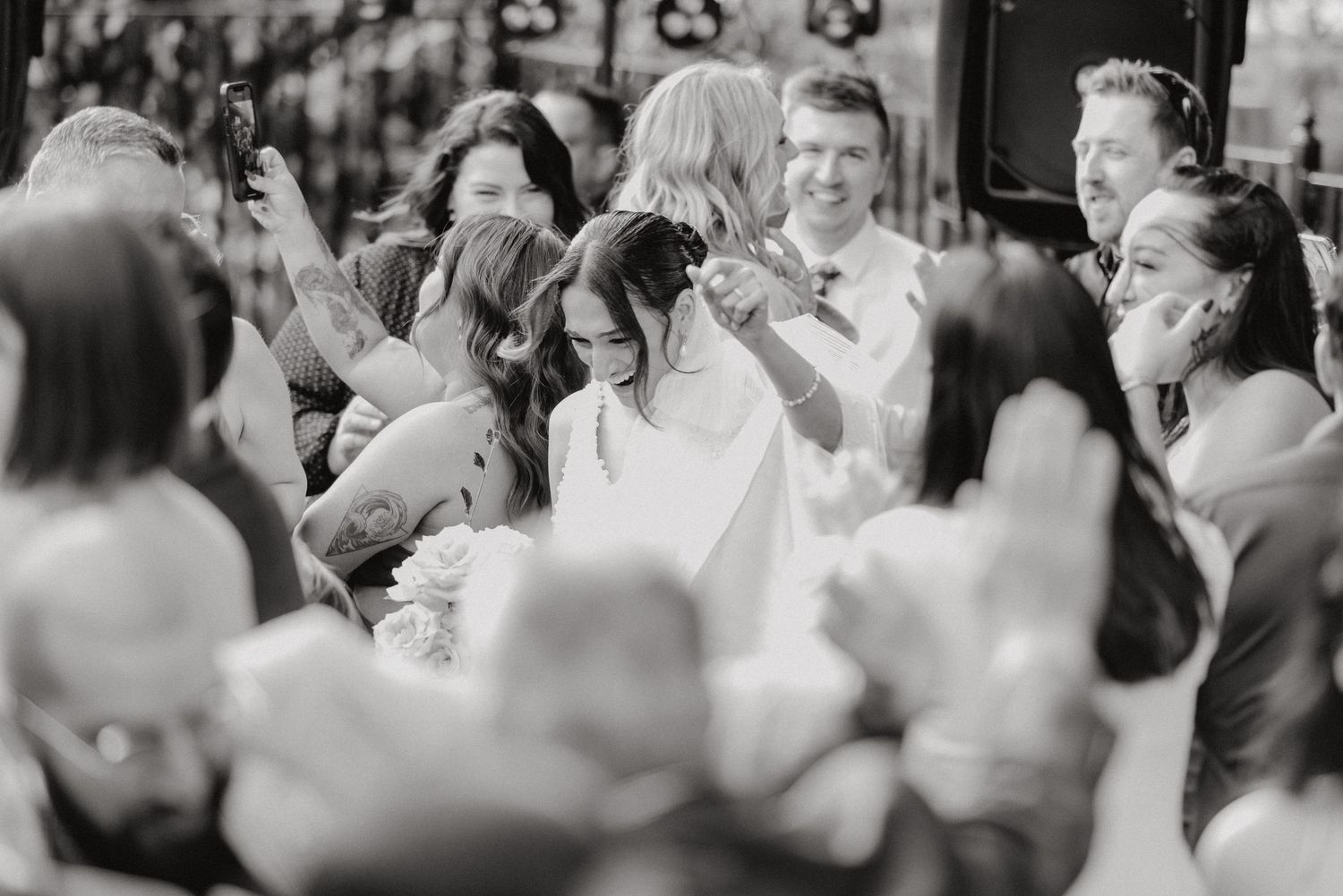 Black and white candid shot of wedding guests dancing and celebrating together.