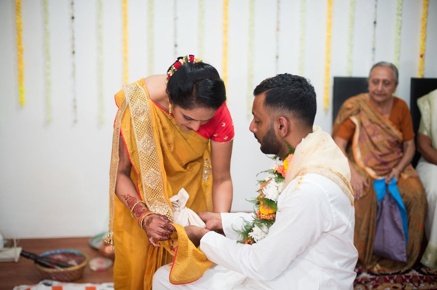 A ceremonial exchange during an Indian wedding with the couple seated on floor cushions.