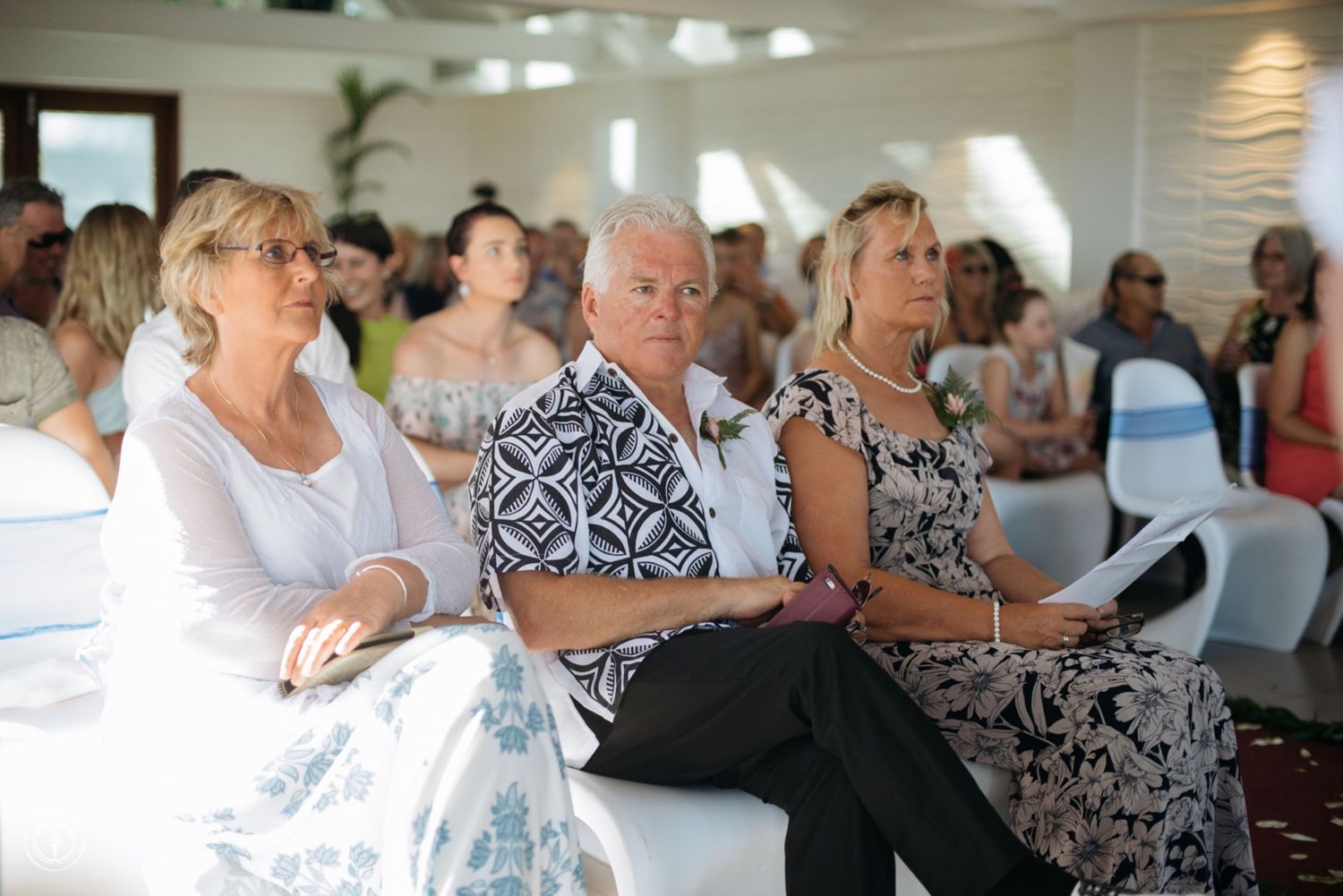 Wedding guests in formal attire seated in rows during the ceremony.