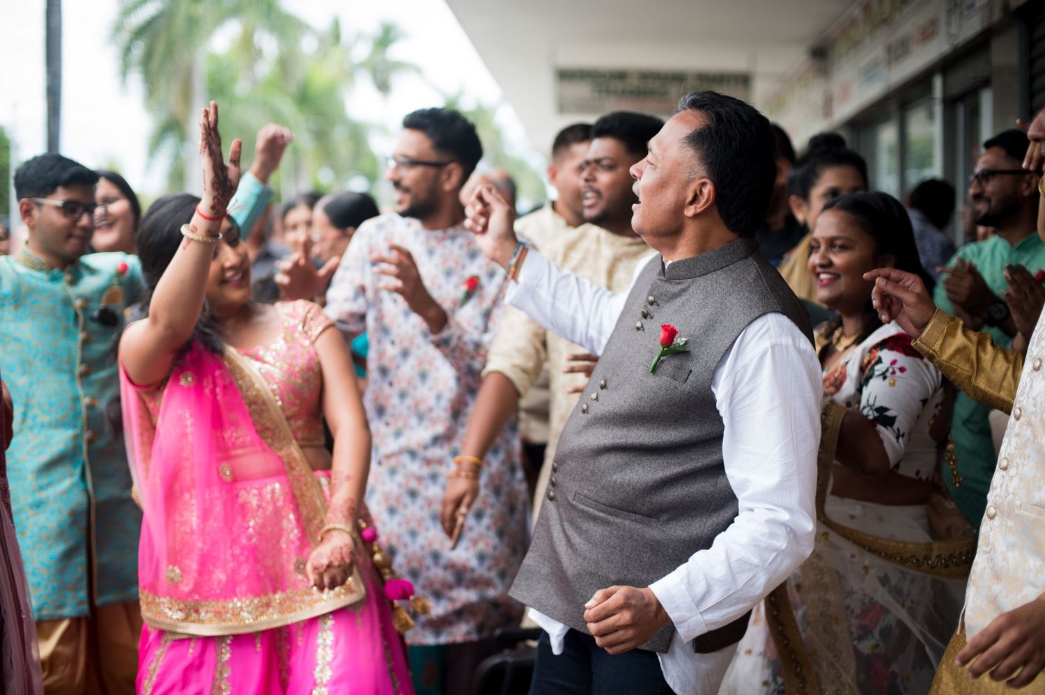 Guests in colorful traditional attire celebrate energetically at an Indian wedding event.