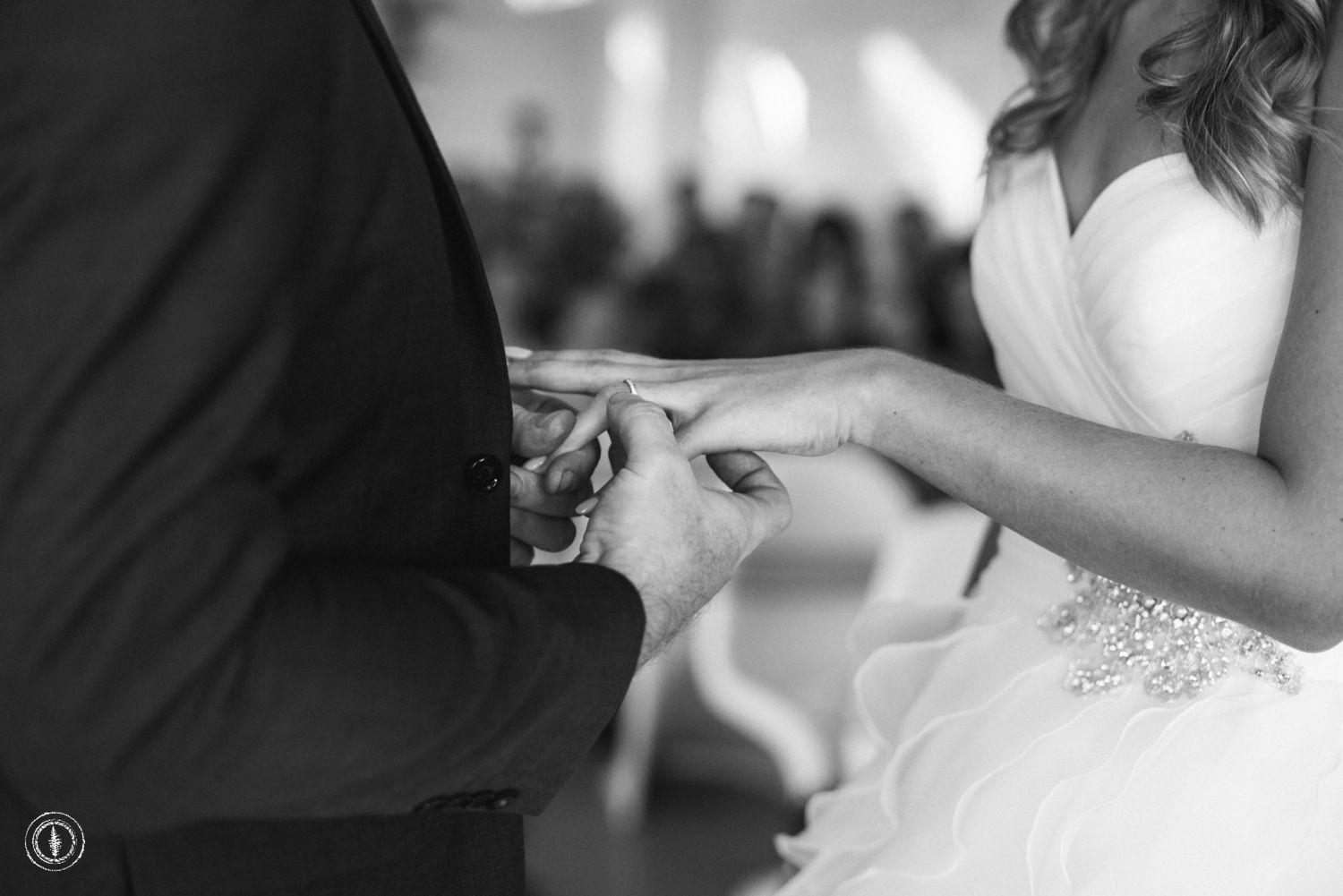 Black and white close-up of wedding ring exchange during ceremony.