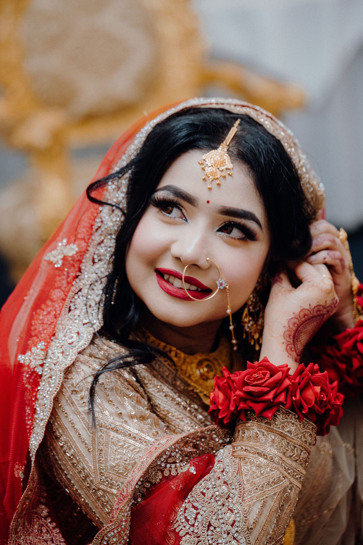 South Asian bridal portrait with red dupatta, traditional jewelry and floral accessories.