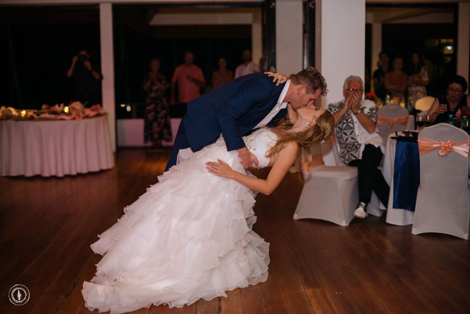A romantic dip captured during a wedding dance on a hardwood floor with twinkling lights overhead.