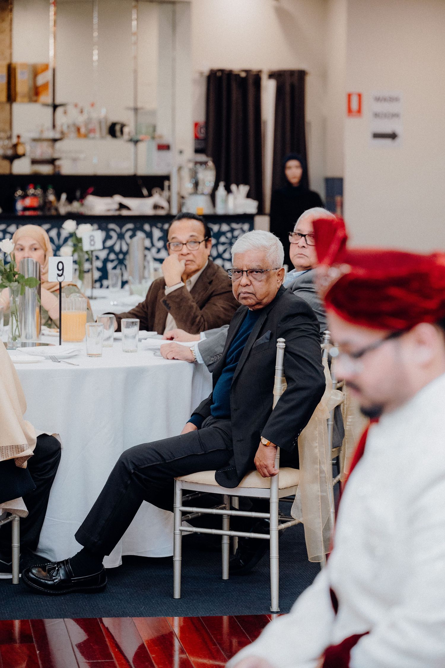 Wedding reception guests seated at decorated round tables with white linens.