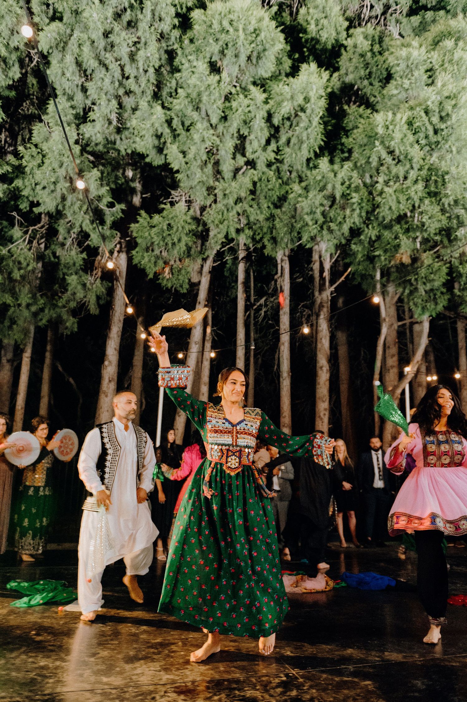 Dancers in traditional folk costumes performing at an outdoor evening celebration.