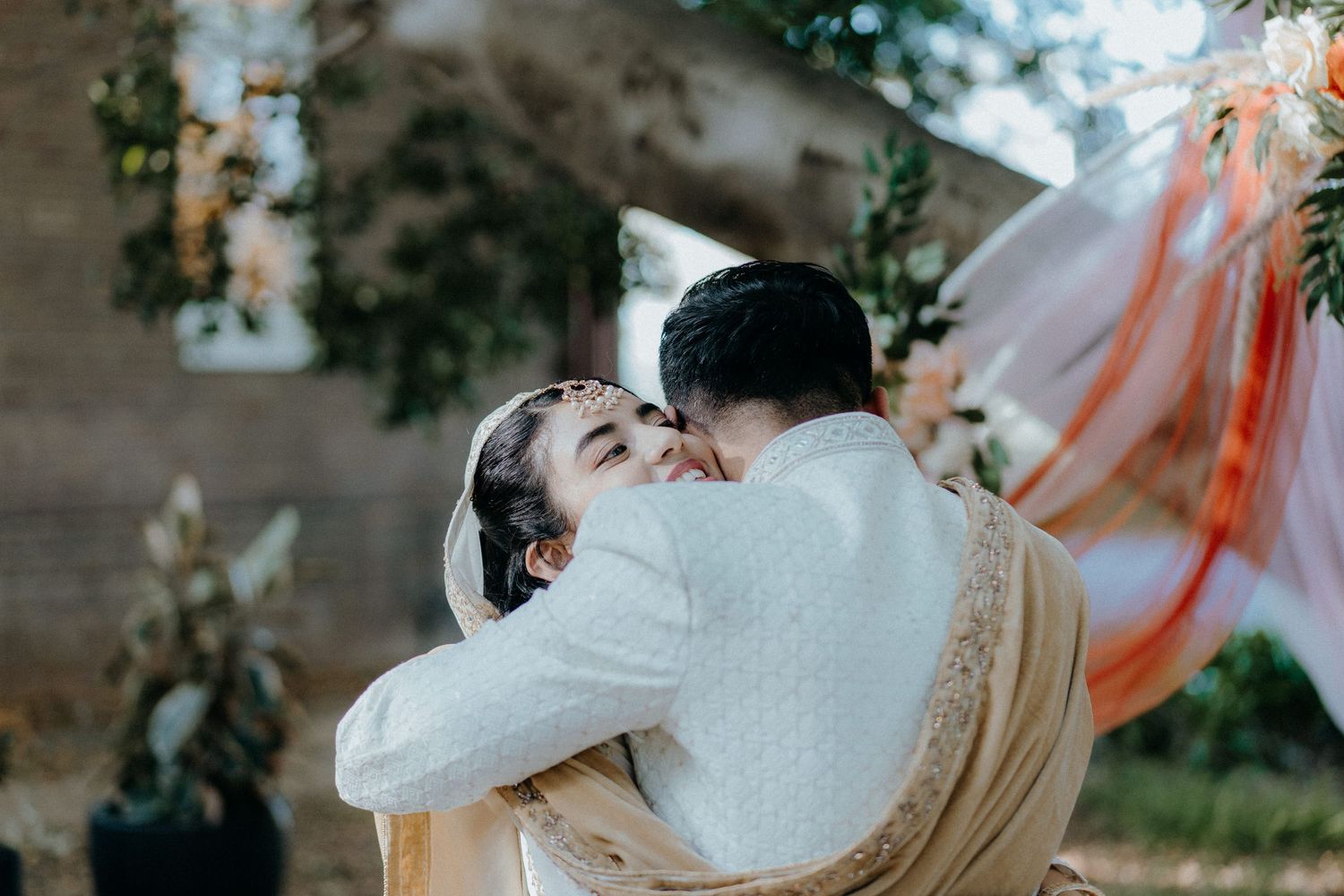 Joyful embrace between newlyweds during their outdoor garden wedding celebration.