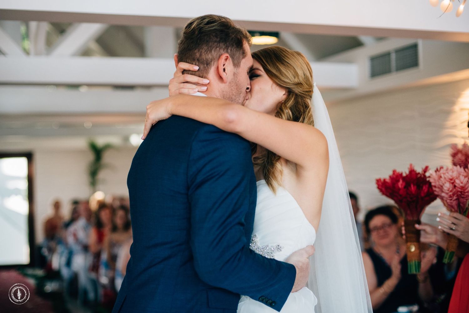 Romantic embrace during wedding ceremony under elegant indoor lighting.
