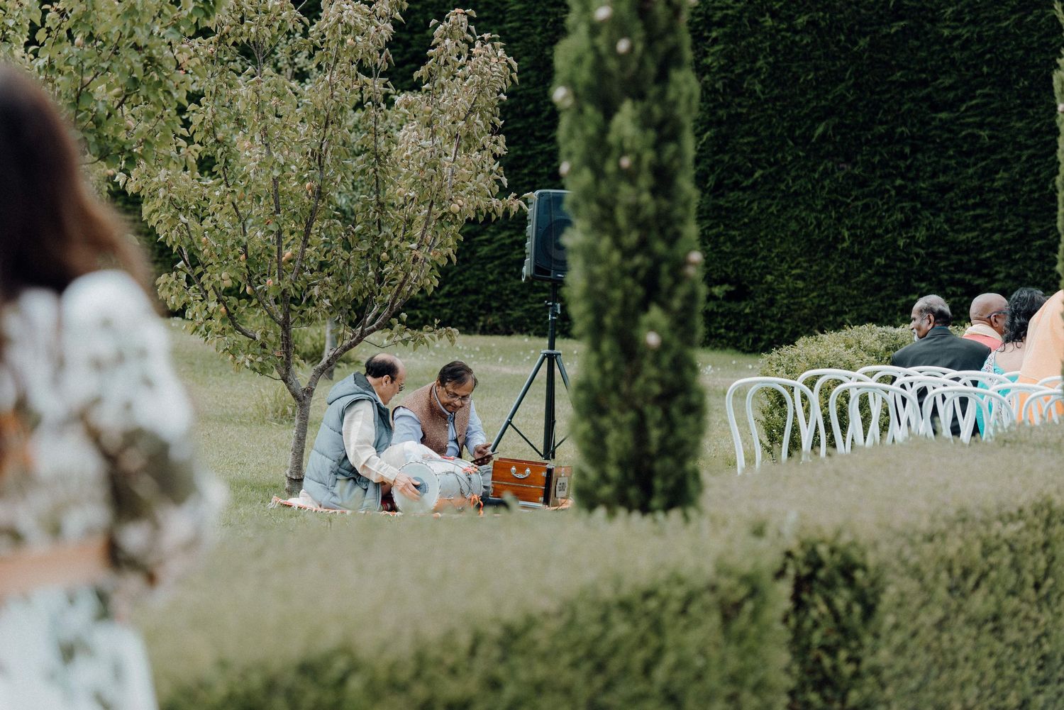 Professional photographer setting up equipment in a manicured garden setting.