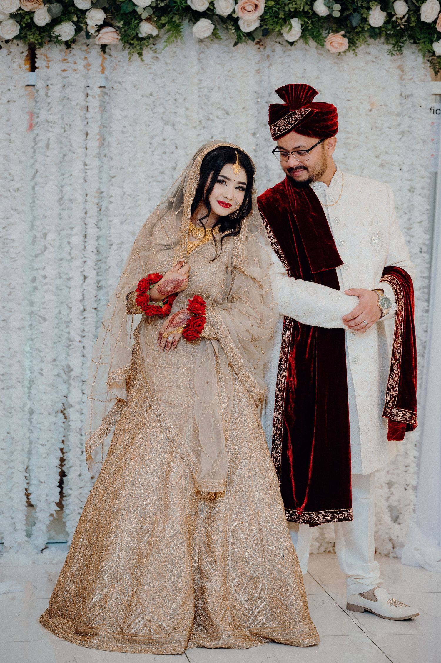 Newlyweds in gold and burgundy wedding attire pose for portraits.