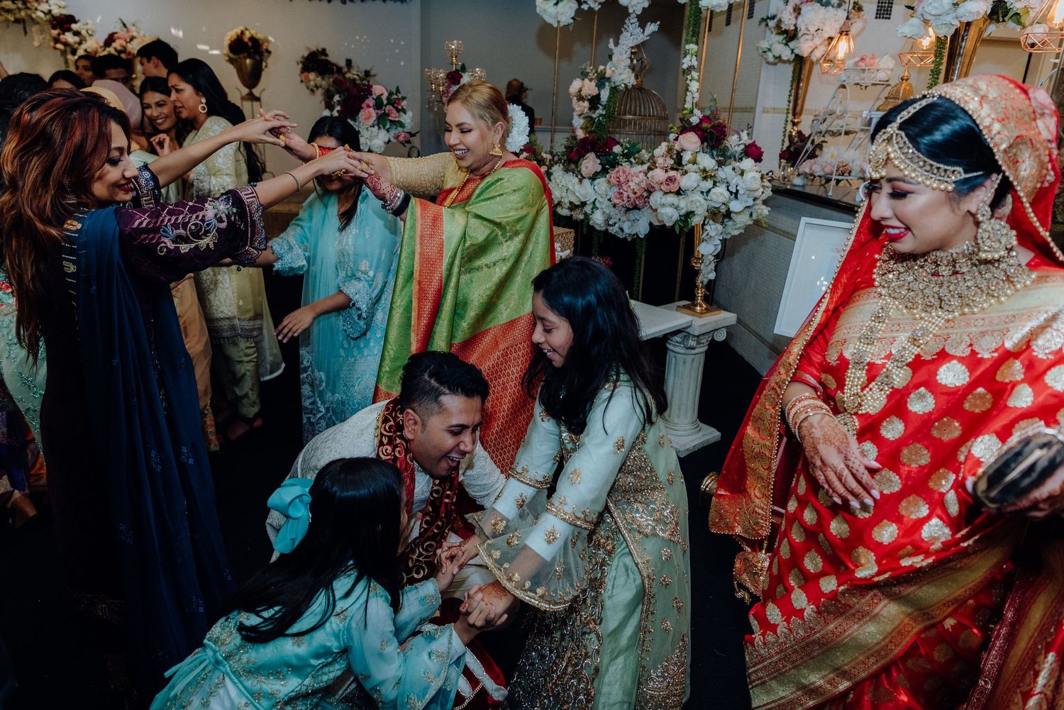 Lively dance floor scene from a multicultural wedding with guests in vibrant traditional attire.