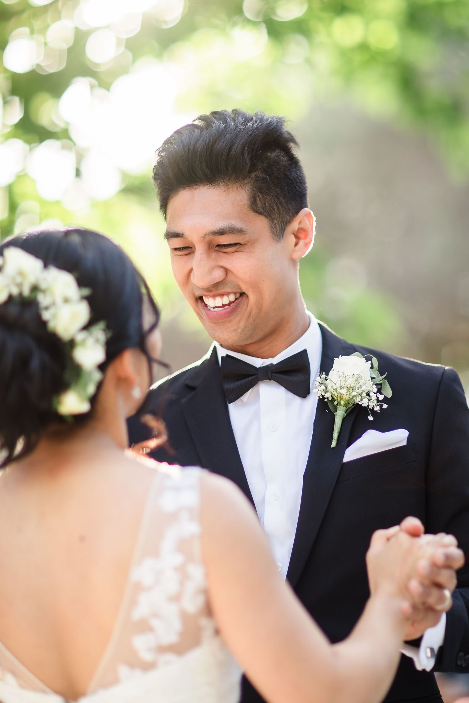 Groom in black tuxedo smiles joyfully at bride during outdoor wedding first dance - Best San Diego Wedding Photographer - Winery