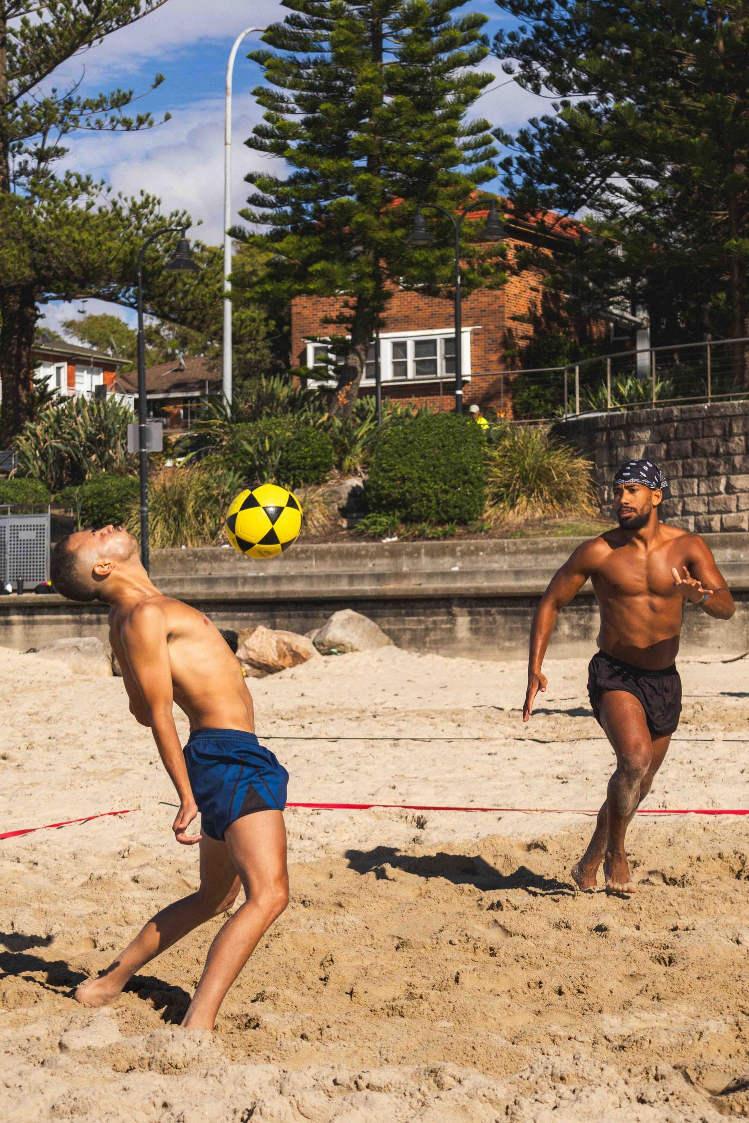 A sequence of volleyball serve action shots on a sandy beach with pine trees in the background.