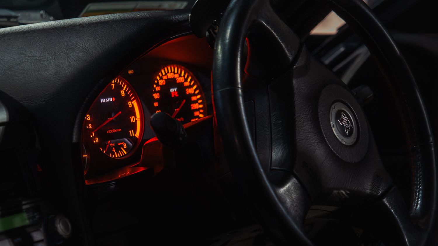 Close-up of a Toyota car dashboard with glowing orange instrument cluster gauges illuminated at night.