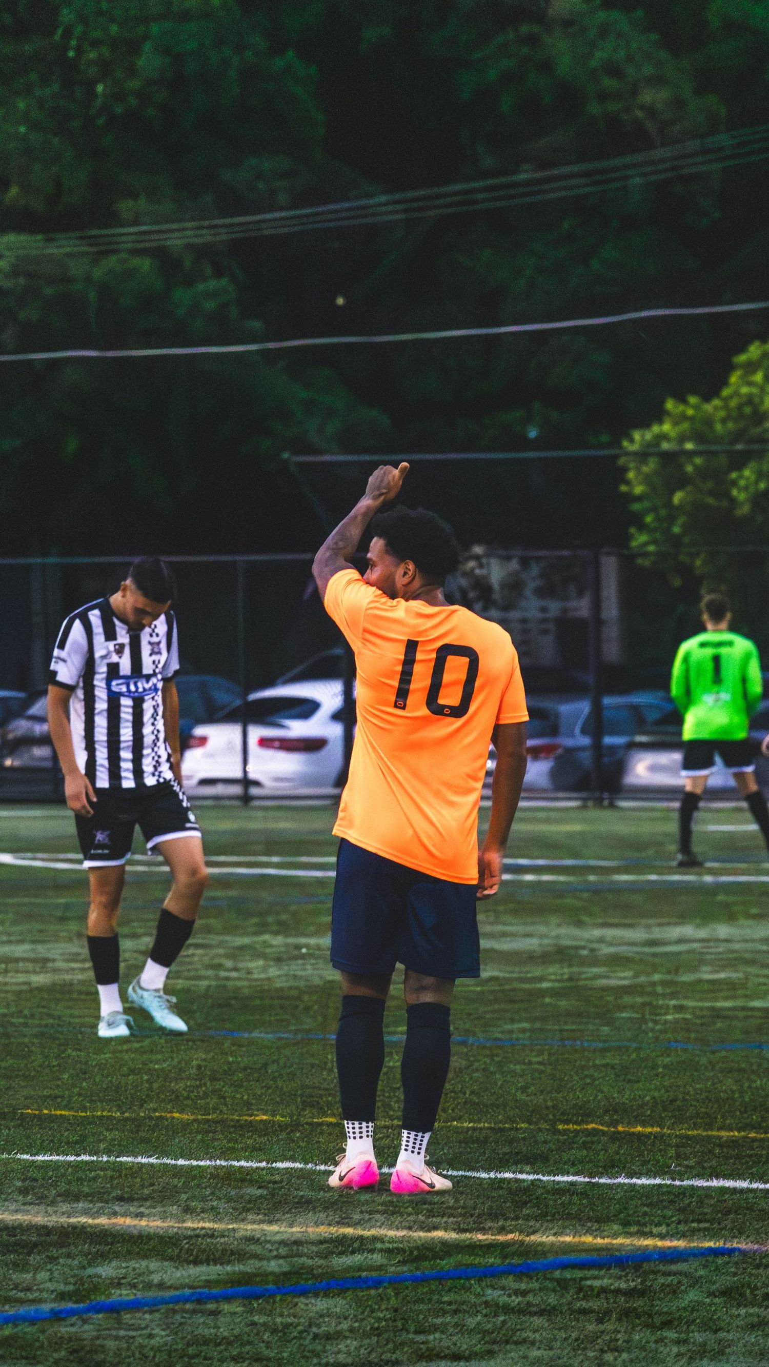Soccer players in orange and striped jerseys stretching on a grass field before a match.