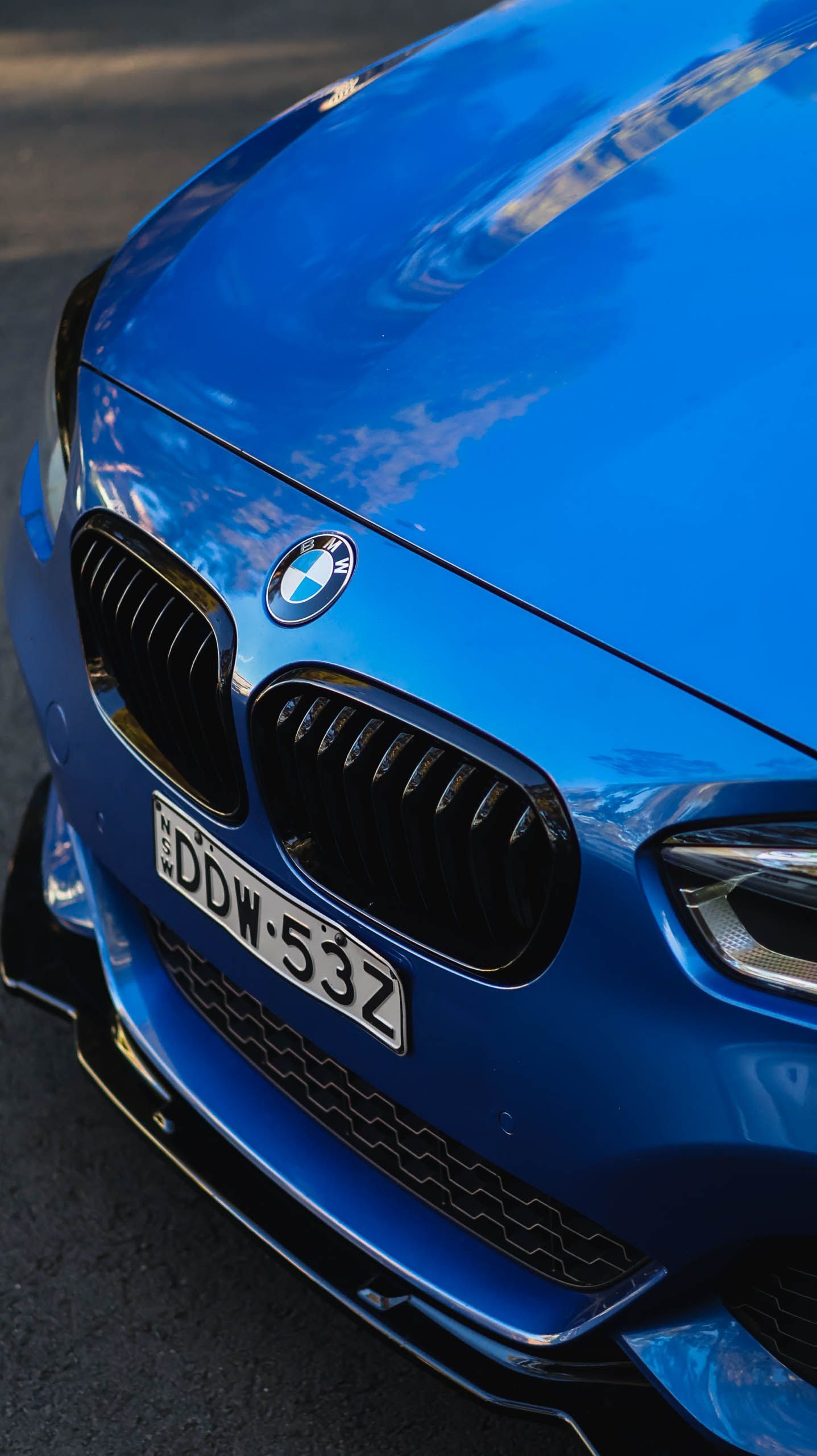 Front view of a blue BMW car with black kidney grilles and license plate DDW-53Z on a dark surface.