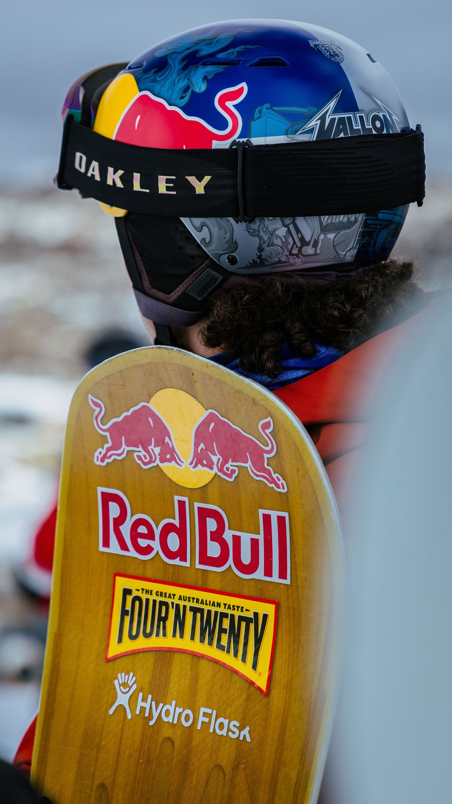Snowboarder wearing Oakley helmet and Red Bull goggles holding a Red Bull Four'N Twenty Hydro Flask sponsored snowboard.