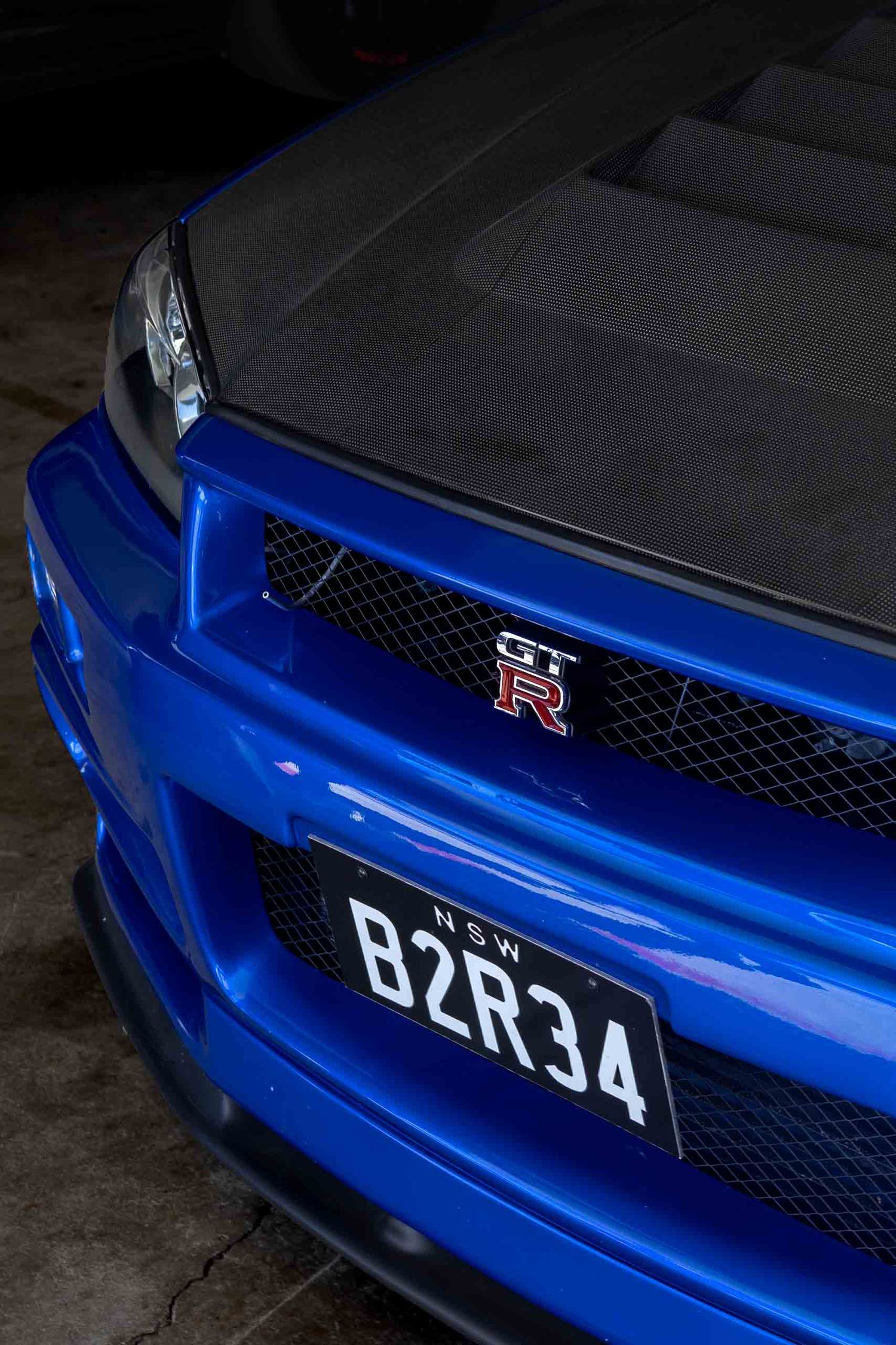 Blue Nissan GT-R with carbon fiber hood and NSW license plate B2R34, front view closeup.
