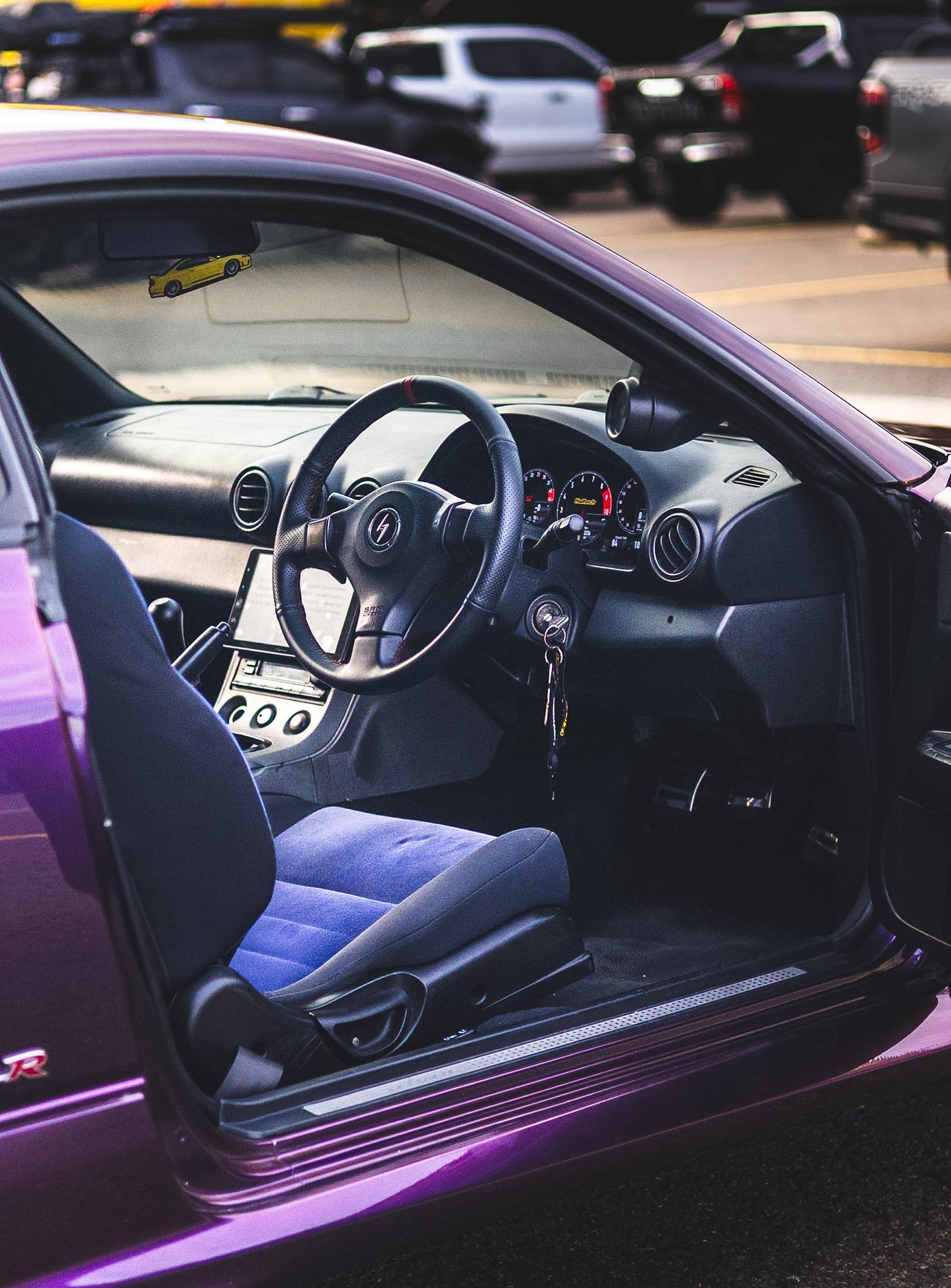 Purple Nissan 350Z sports car interior details showing dashboard, steering wheel and black leather seats.