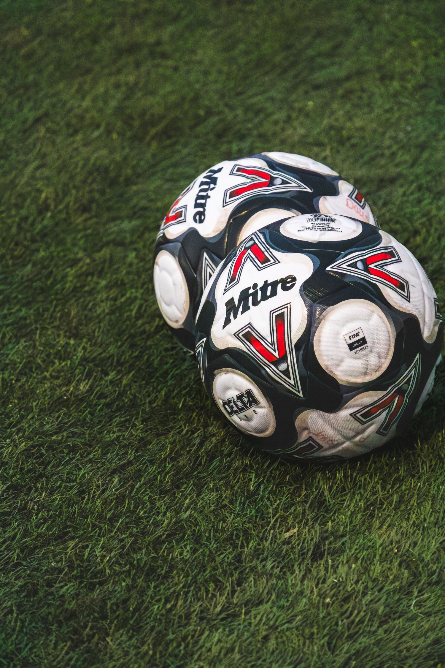 A sequence of identical white and black soccer balls lying on green grass showing different angles and perspectives.