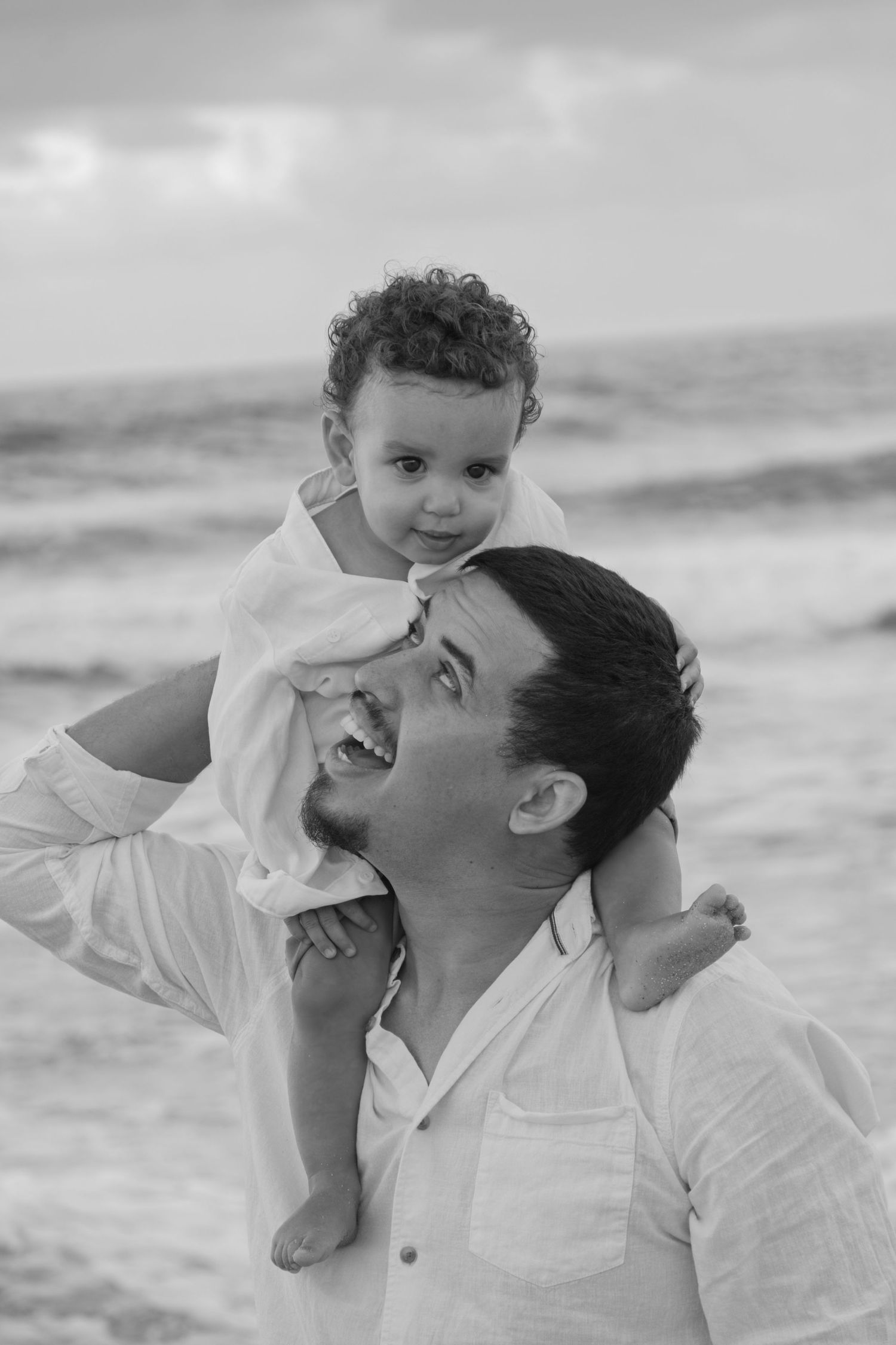 Black and white beach portrait showing joyful interaction between parent and child.