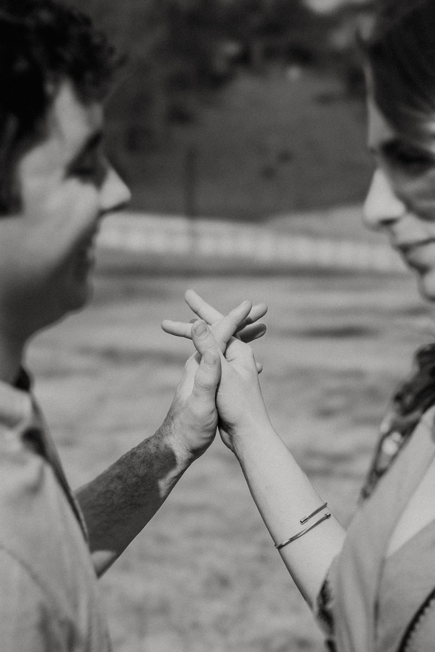 Two people share an intimate moment as they touch hands together in a black and white photograph.