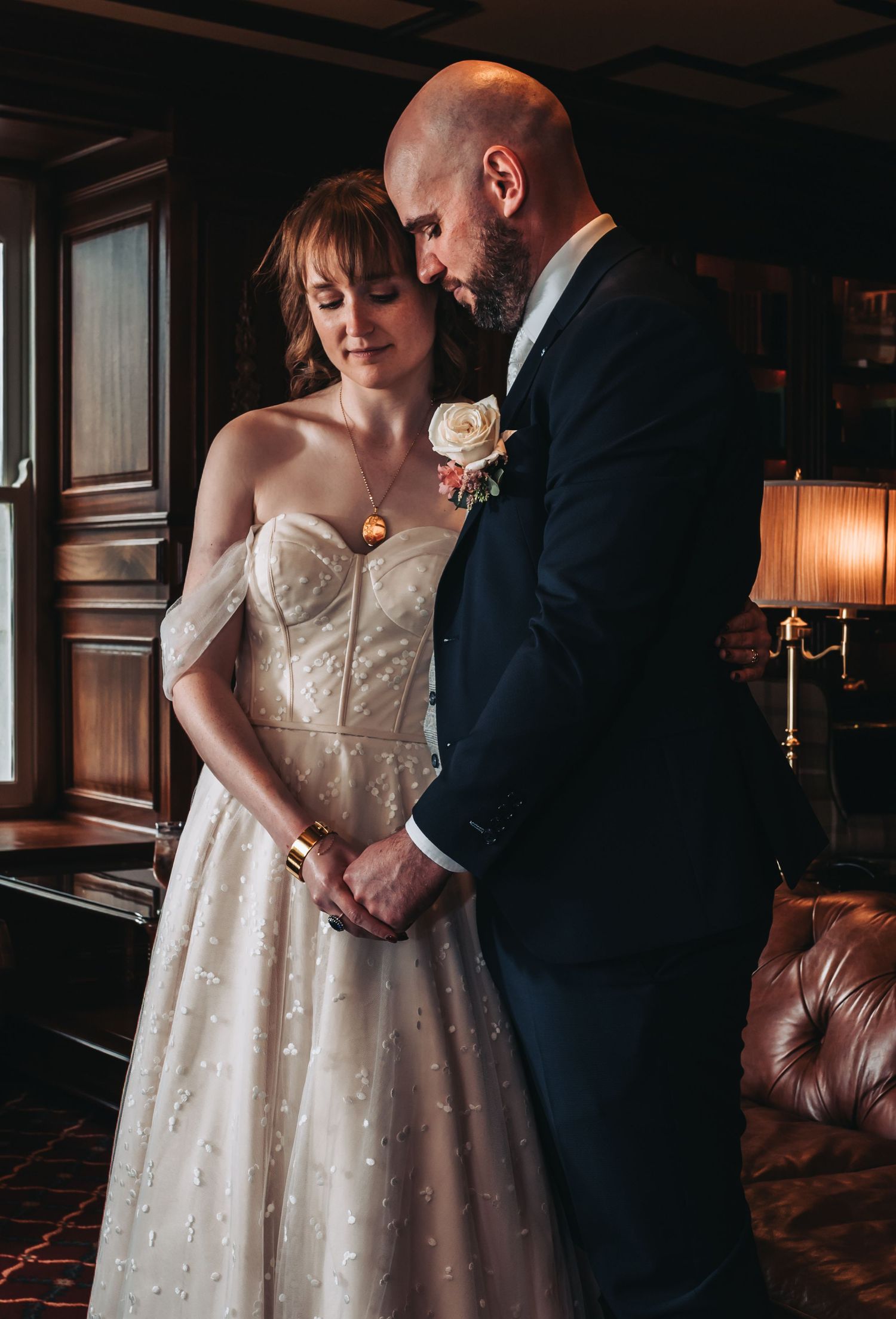 Intimate wedding portraits captured in moody lighting with vintage leather furniture.