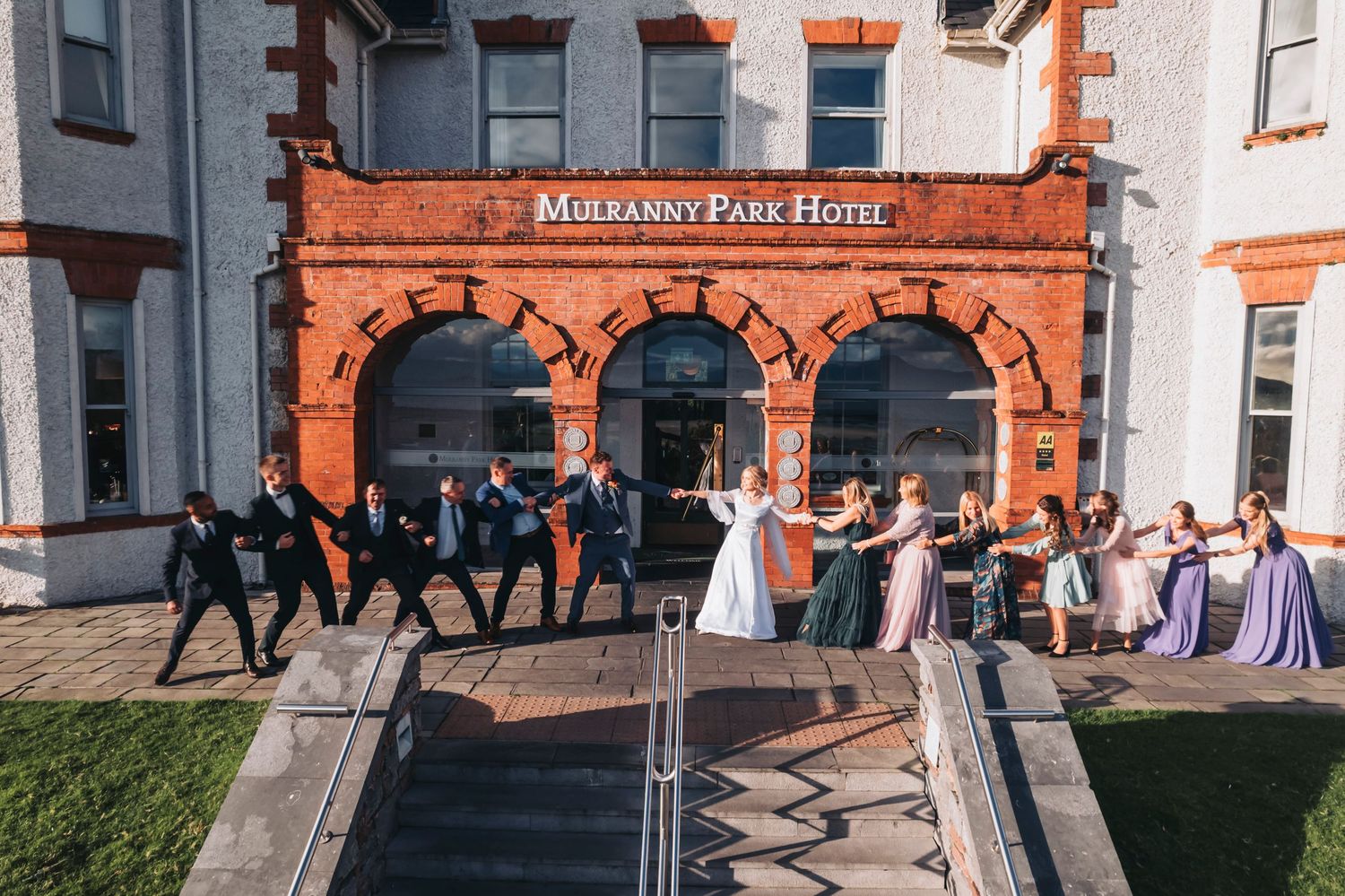 Historic red brick building entrance with decorative archway and gathering area.