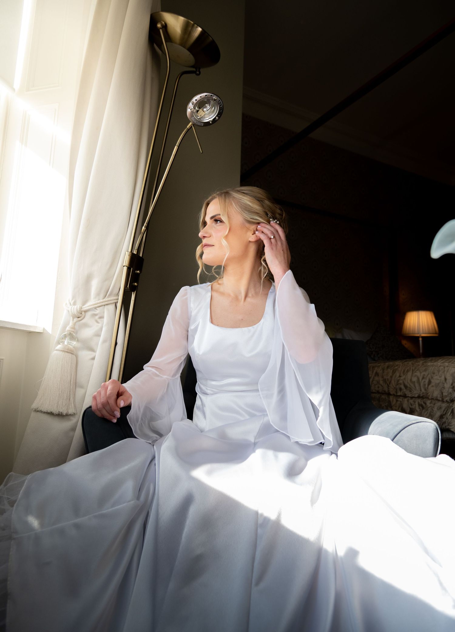 Natural light streams through windows illuminating a white wedding dress.