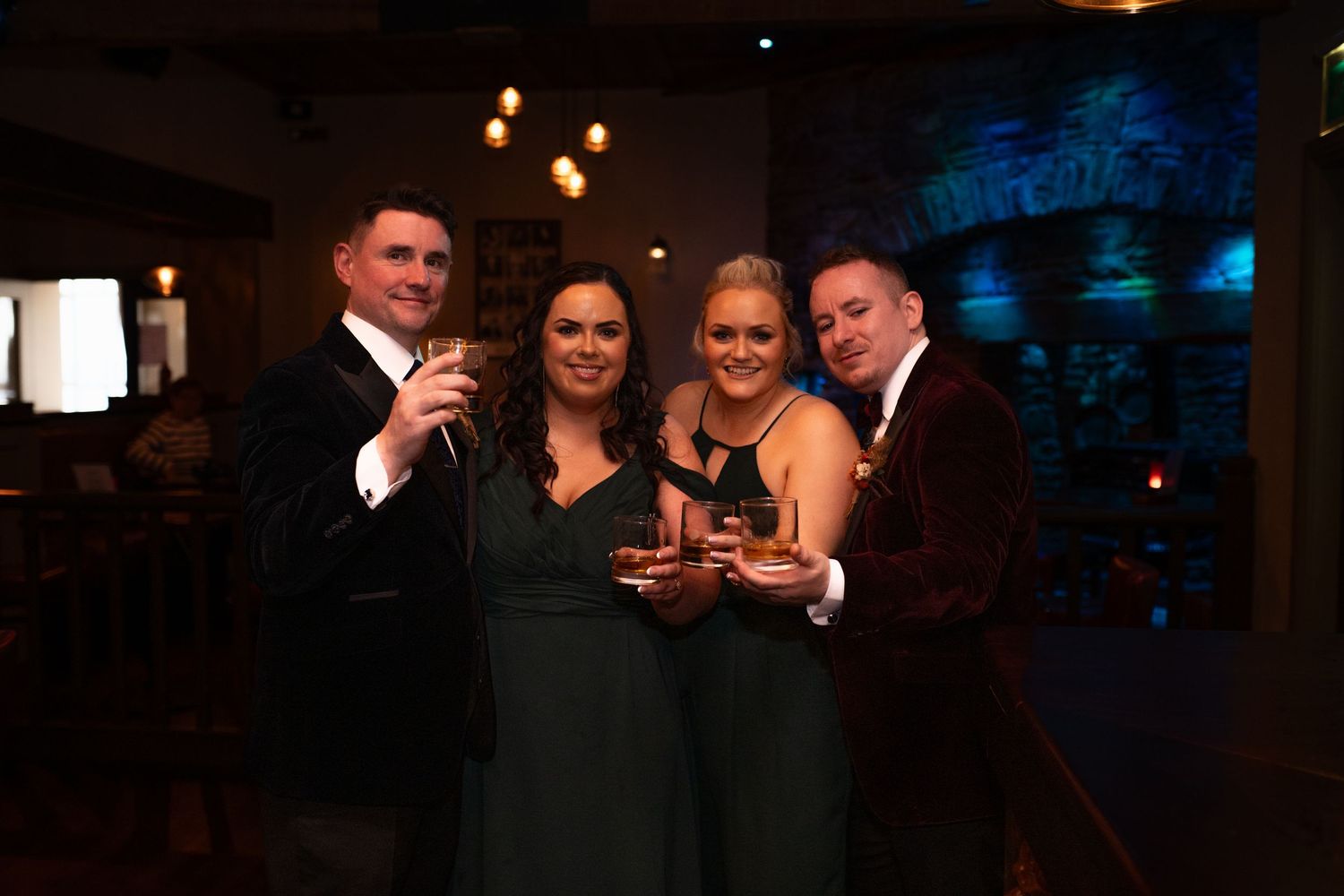 Four elegantly dressed people smiling and holding drinks at a formal evening event.