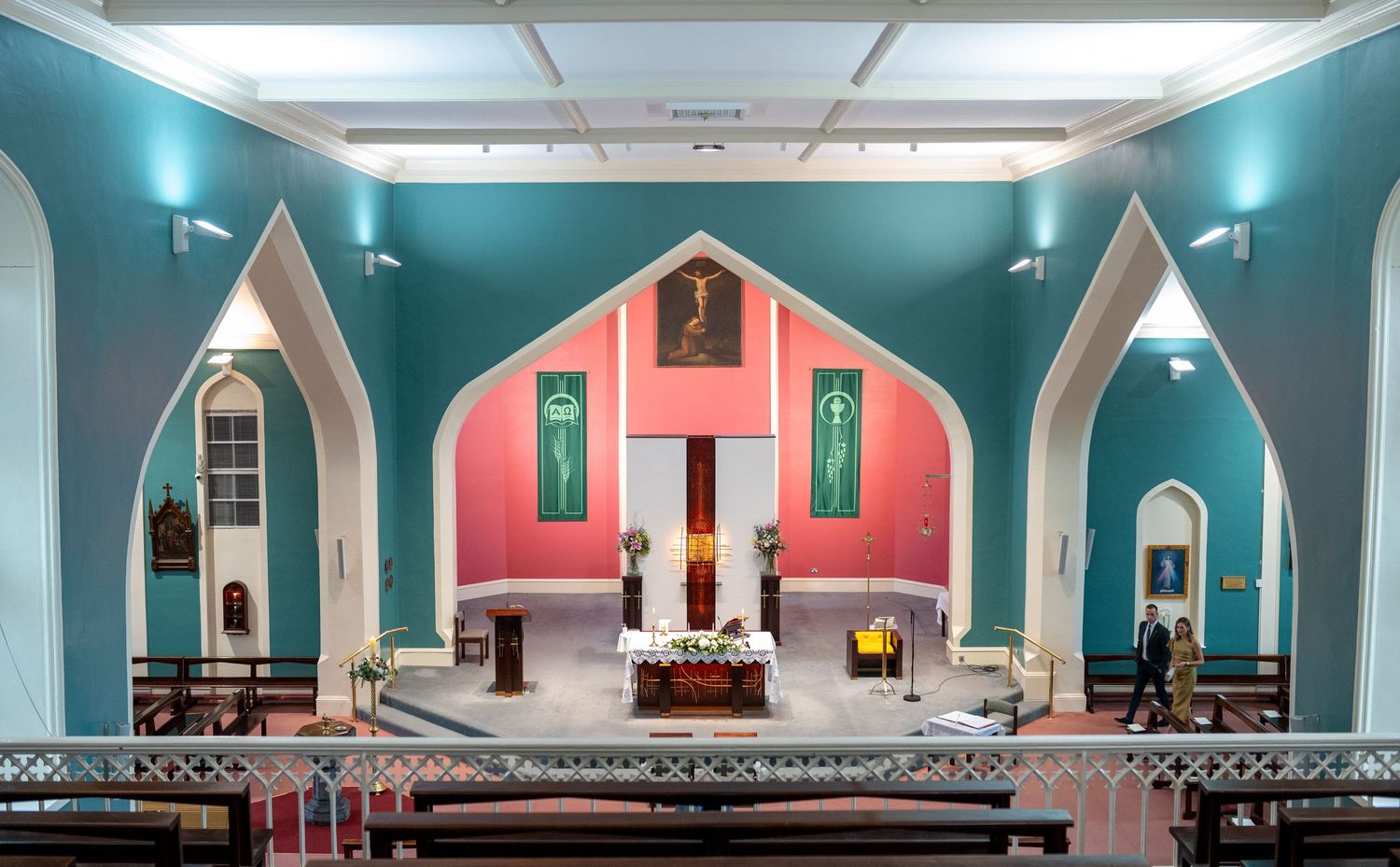 Colorful church interior with teal walls, pink altar, and Gothic arches.