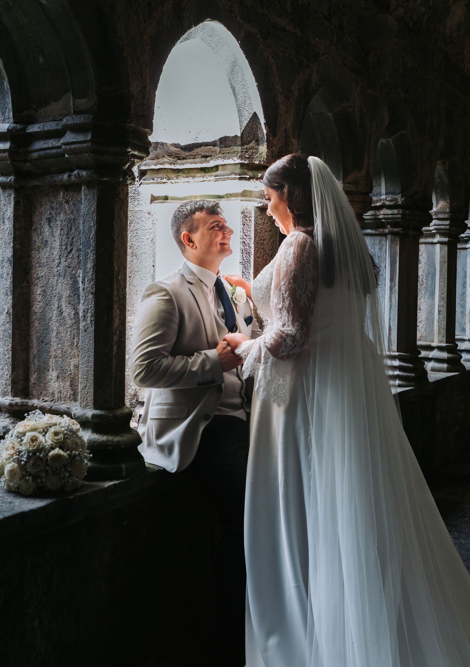 Bride and groom sharing romantic moment in historic stone archway wedding portrait.