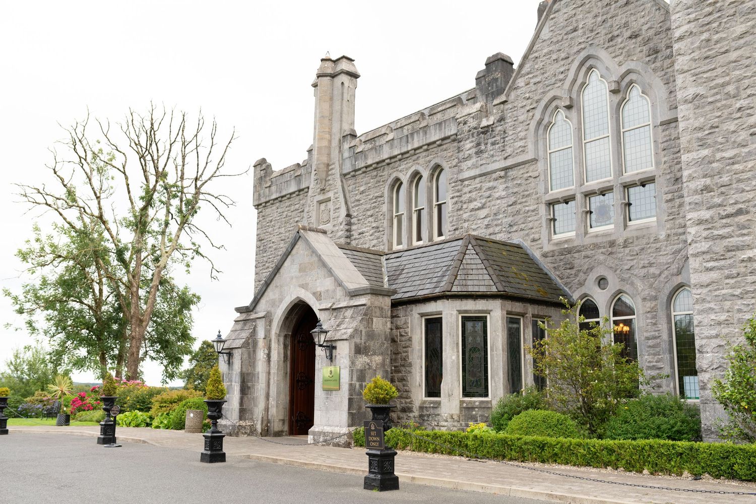 Exterior view of a grand Gothic stone church with arched windows and landscaped grounds.