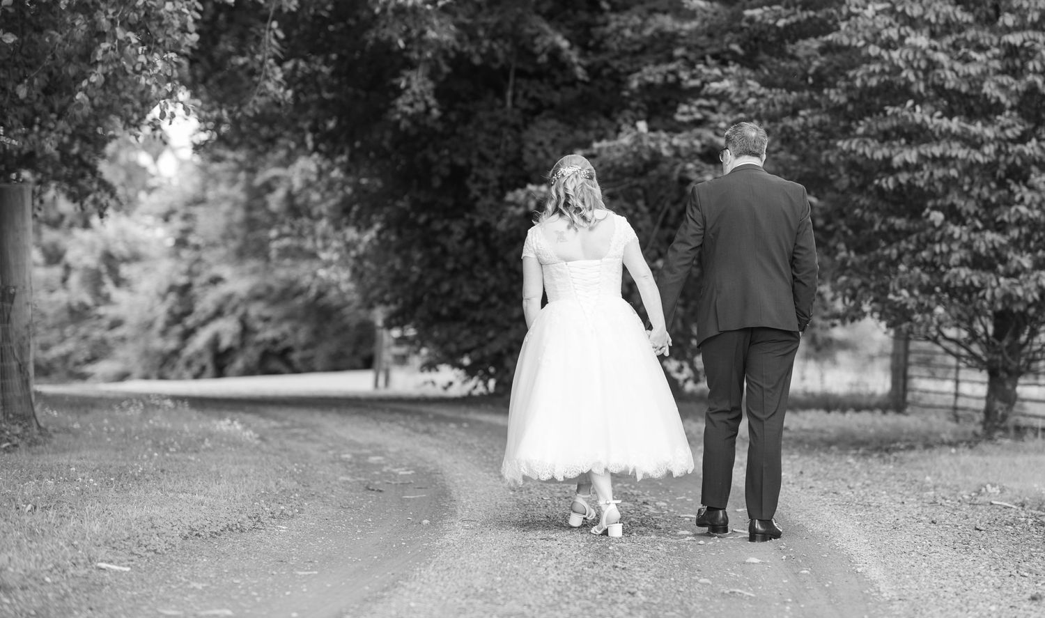 A couple strolls down a winding garden path in black and white photography.