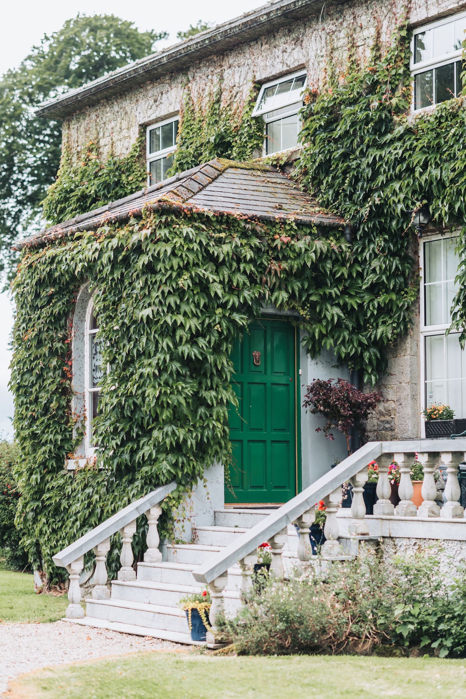 Ivy-covered building exterior with green doors, white steps, and classic architectural details.