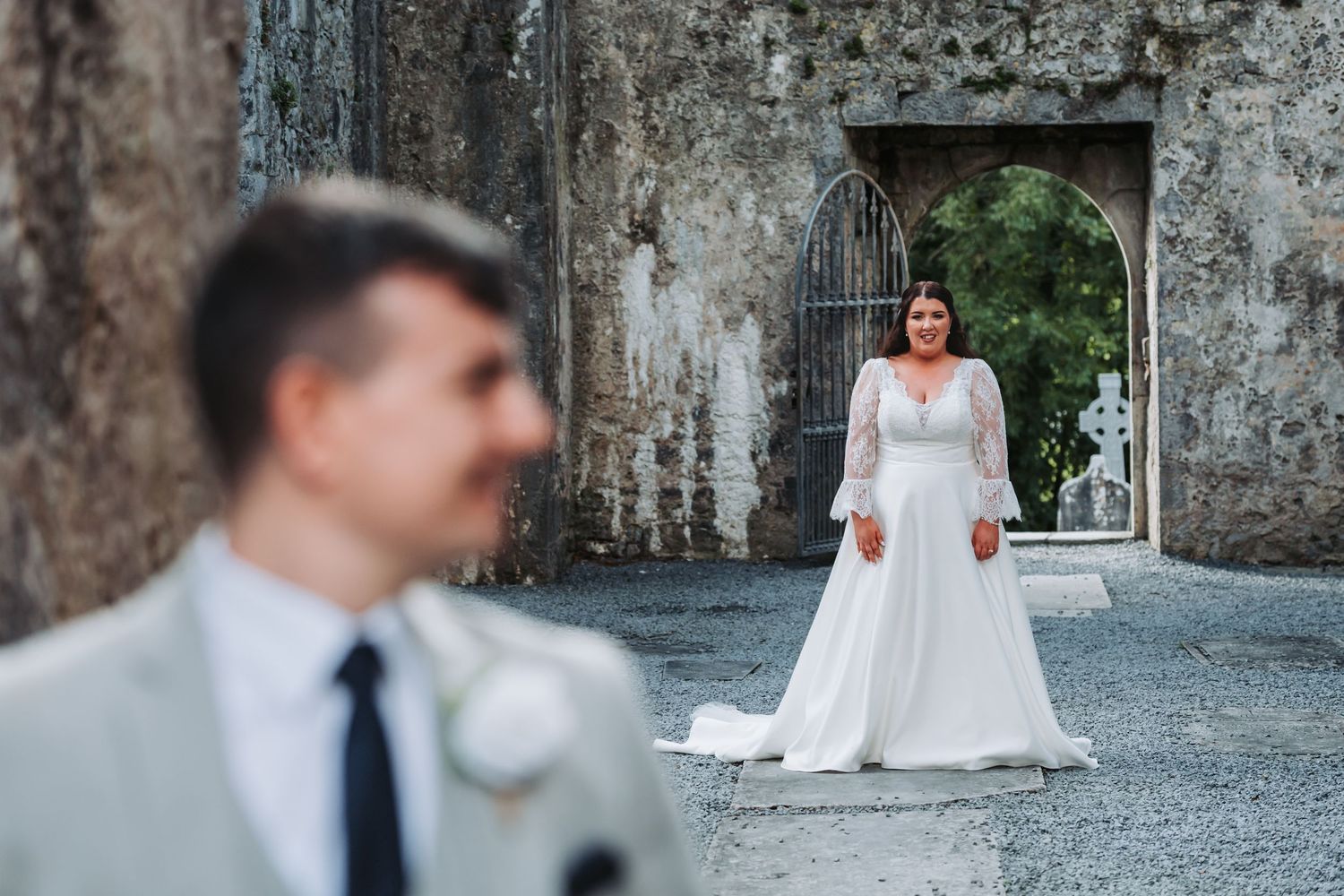 A romantic wedding photoshoot in a stone archway corridor with dramatic lighting and shadows.