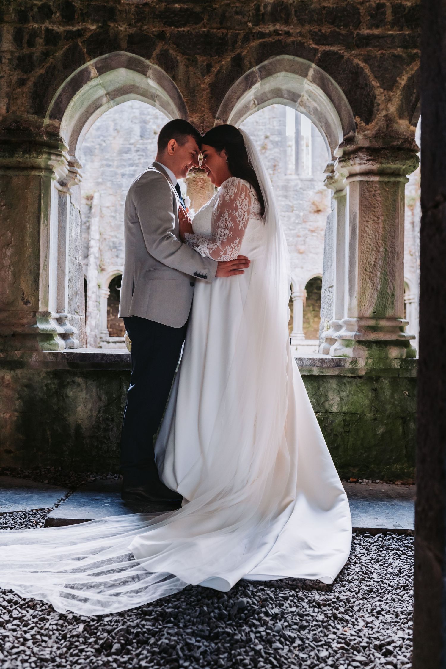 Wedding couple poses under stone archways with dramatic architectural details.