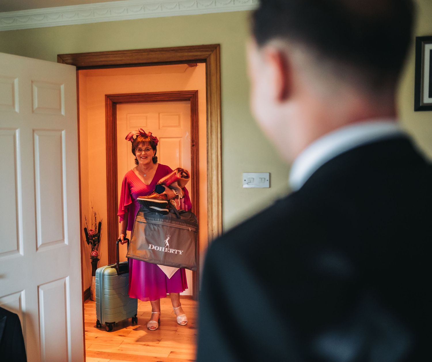 Someone in red holding a sign while standing in a doorway as another person looks on.