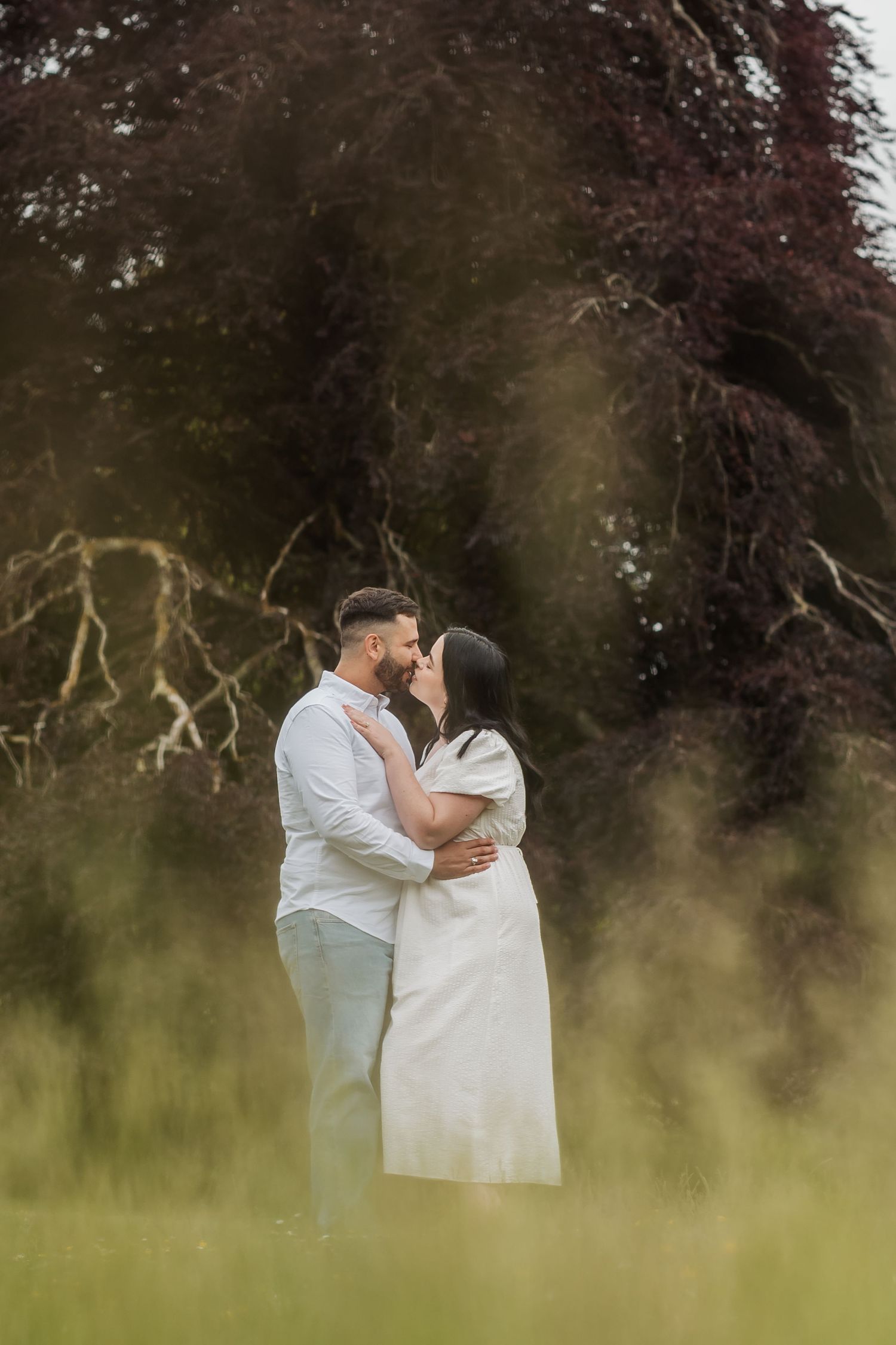 Romantic couple embracing in a dreamy garden setting with soft focus foreground.