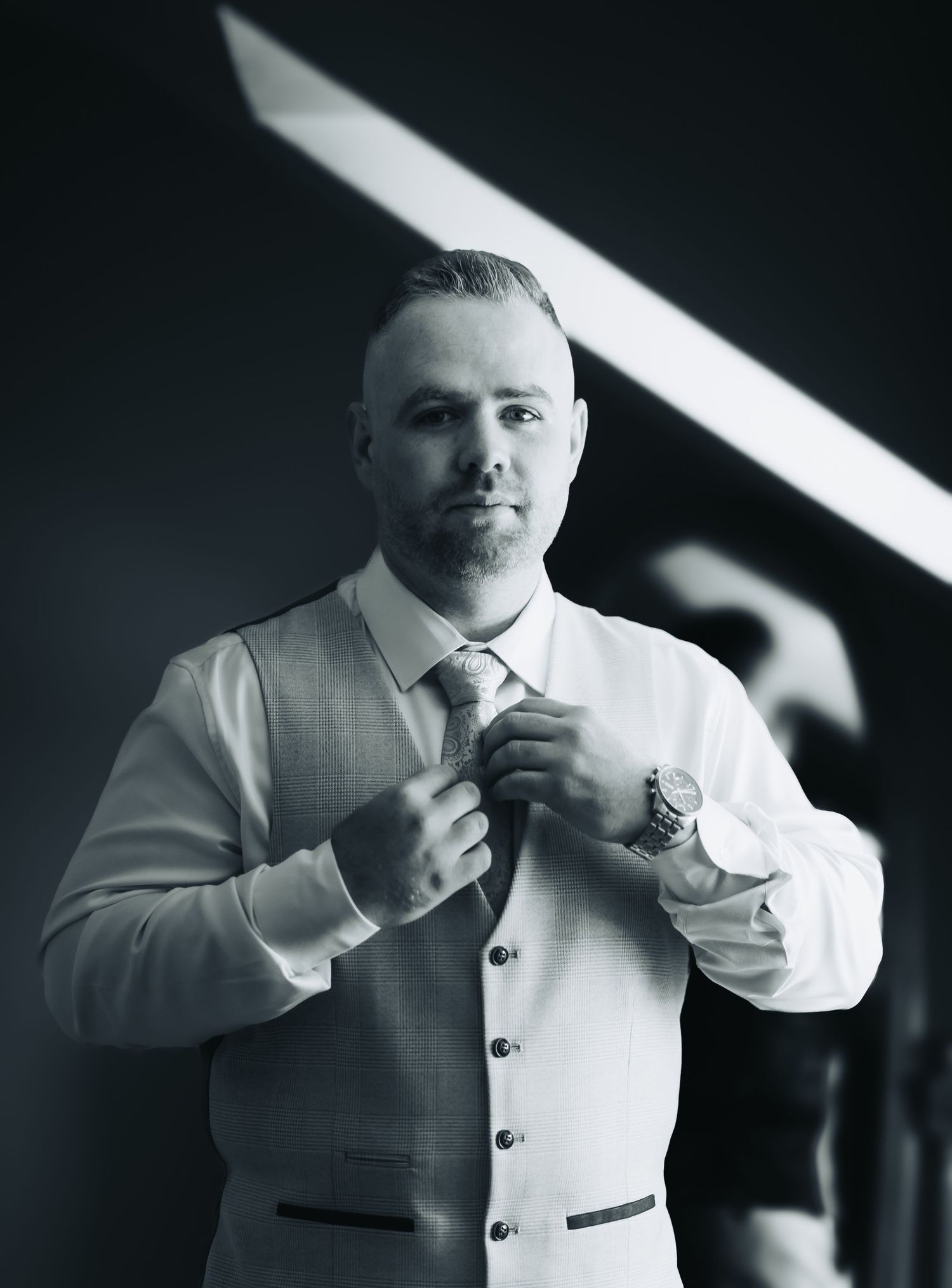 Sequence of black and white photos showing details of adjusting a white formal suit and tie.