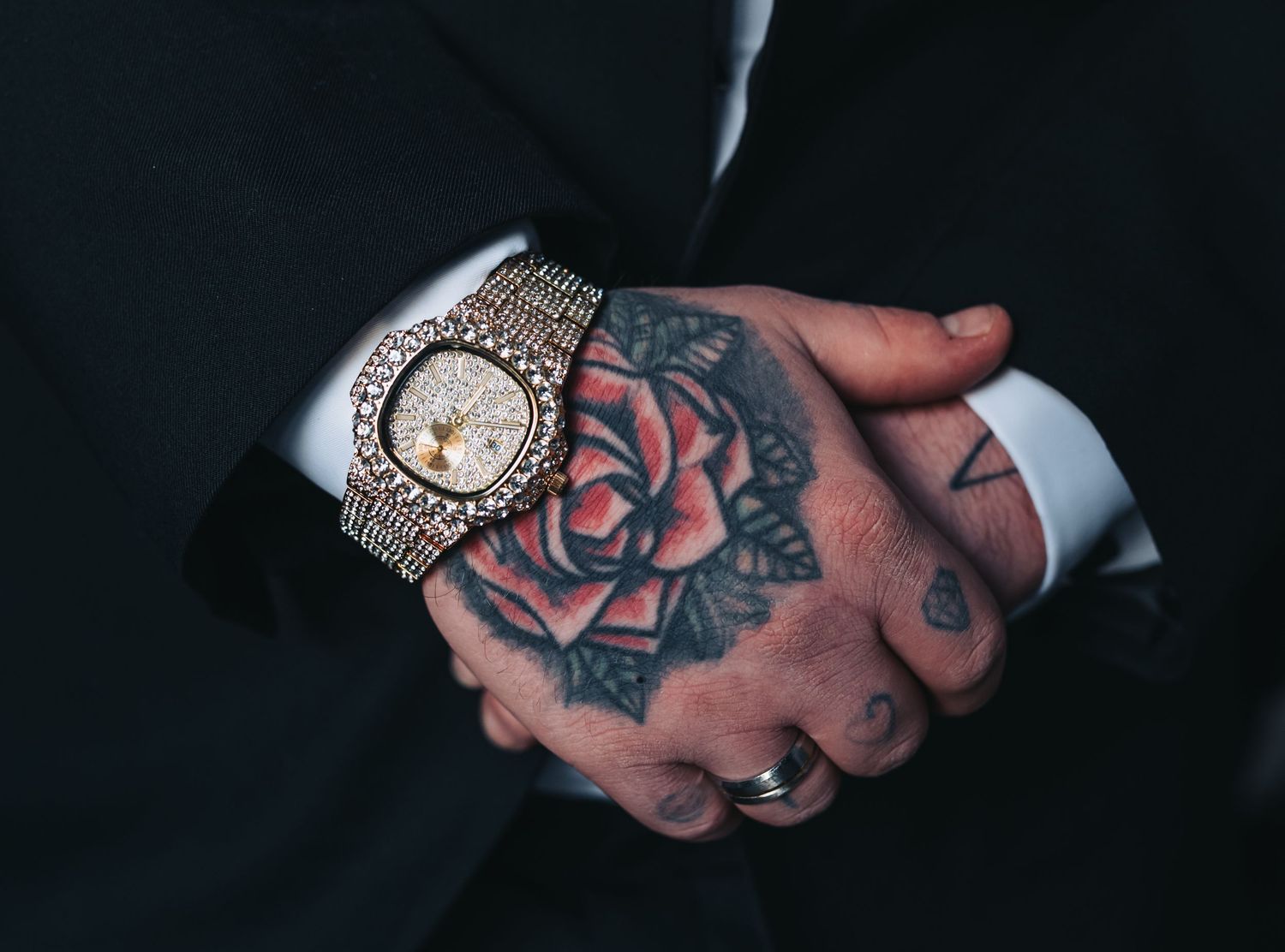 Detailed shots of tattooed hands wearing formal accessories and jewelry.