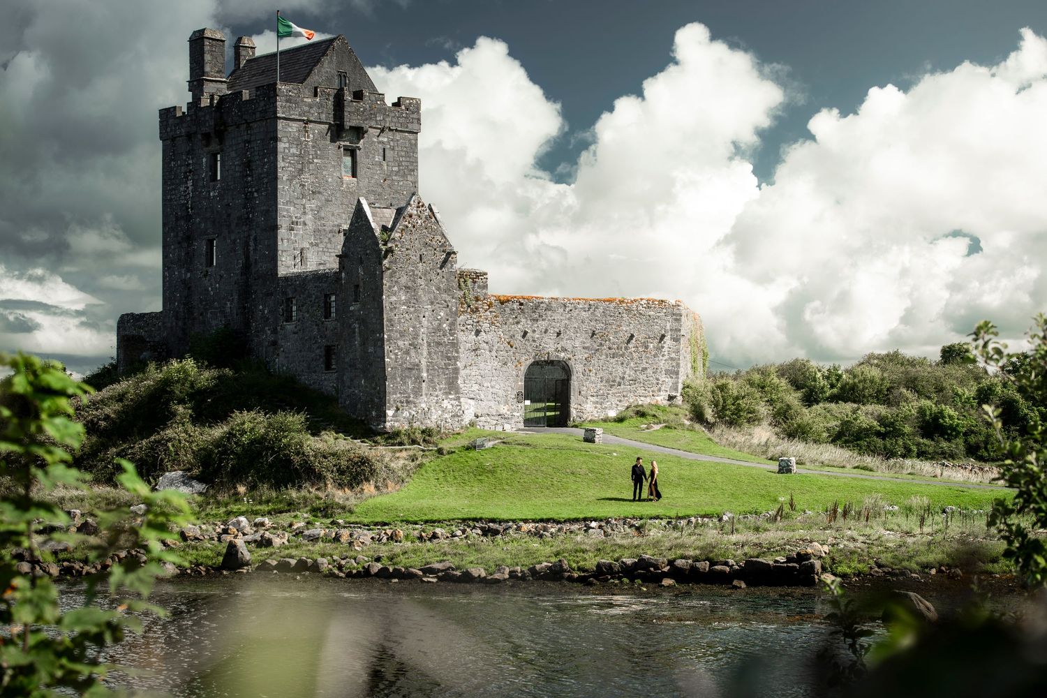 Ancient stone castle ruins under dramatic cloudy skies in rural countryside setting.