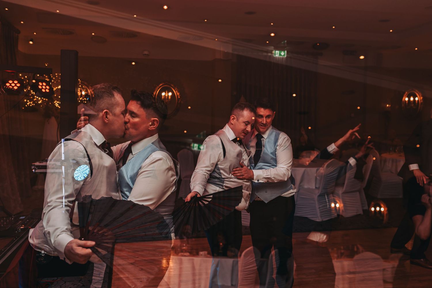 Wedding reception dance floor filled with celebrating guests under dimmed lighting.